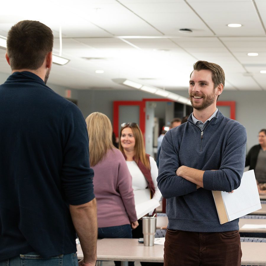 Horton employee with his arms crossed speaking with a co-worker in a Horton breakout room setting