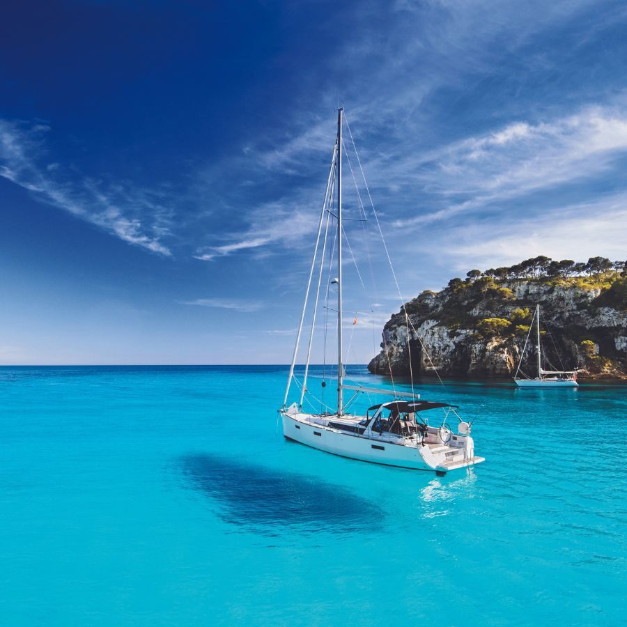 Sailboat anchored in the deep blue waters of a cove.