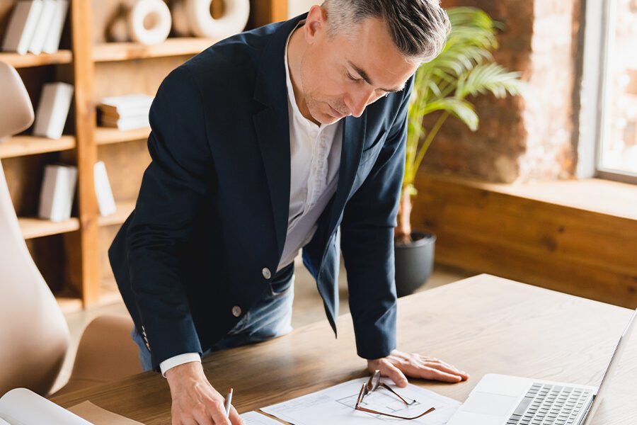 A professional holding a blueprint with an insurance icon in the background.