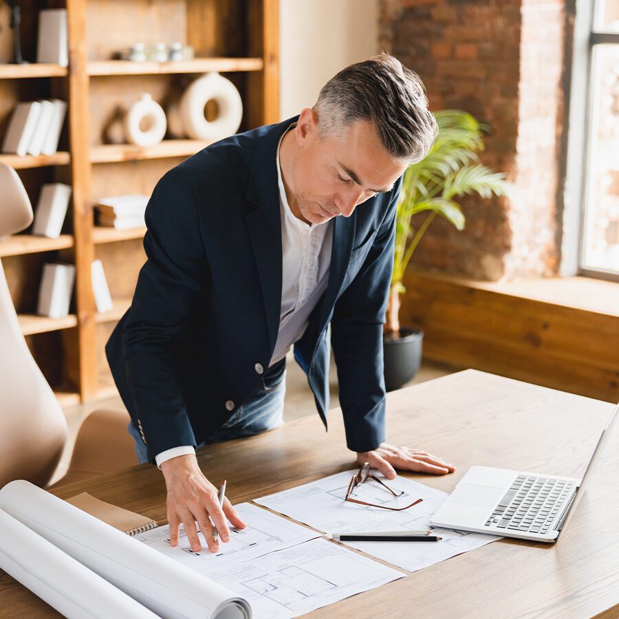 A professional holding a blueprint with an insurance icon in the background.