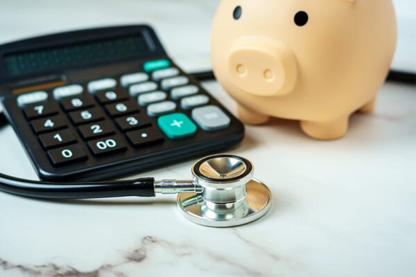 A photo of a calculator, stethoscope and piggy bank.