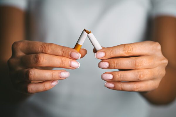 Woman holding broken cigarette in hands.